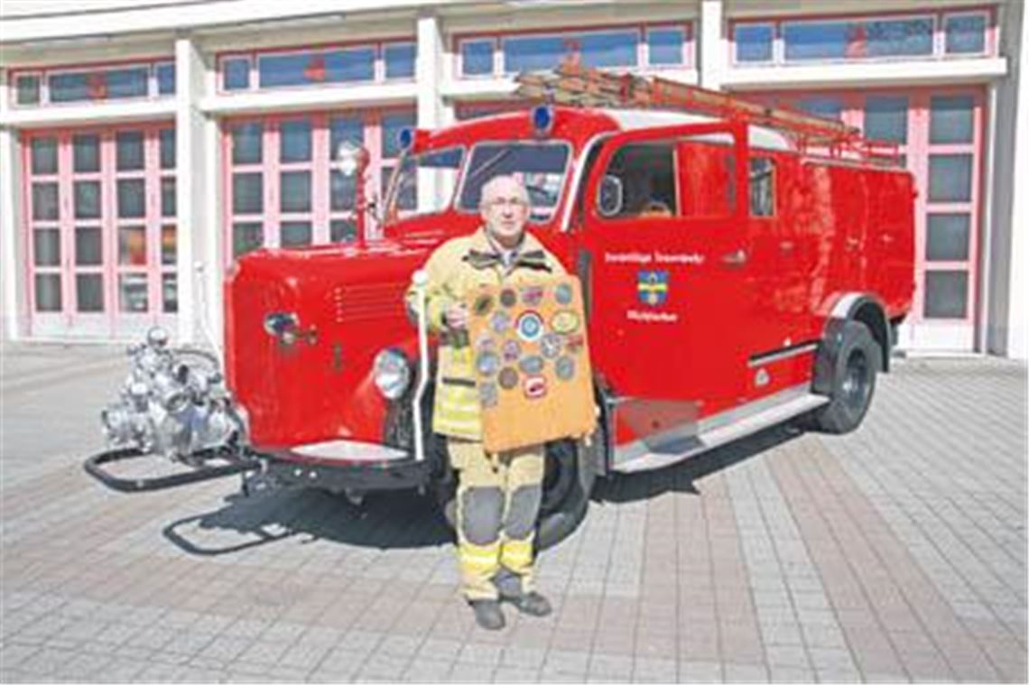 Wilfried Müller mit dem historischen Löschfahrzeug und Plaketten von Oldtimertreffen. Foto: Sadler