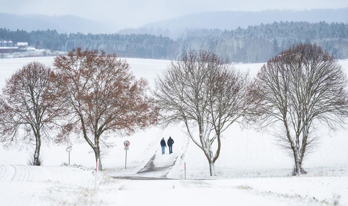 Winterwetter bei Bösingen: Fußgänger auf verschneitem Weg im Schwarzwald.