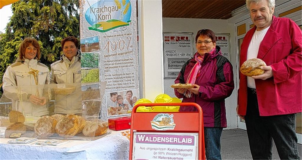 Wolfgang Braun bietet einen Waldenserlaib an. Ein Teil des Erlöses fließt in die Sanierung der Kirche. Angela Bassier (2. v. li.) von der Kirchengemeinde freut sich über das Engagement. Foto: privat