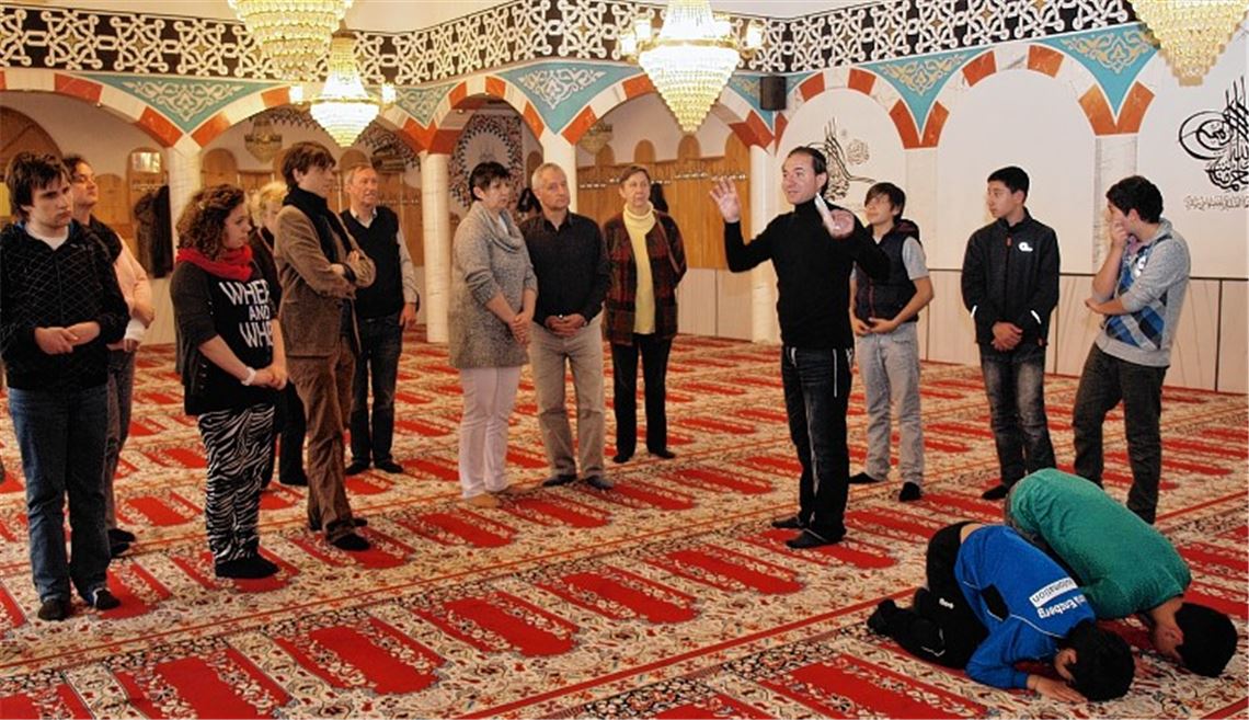 Yilmaz Cebeci führt durch die Moschee, erläutert Schriftzeichen an Wänden und Decke und beschreibt den Ablauf von Ritualen.