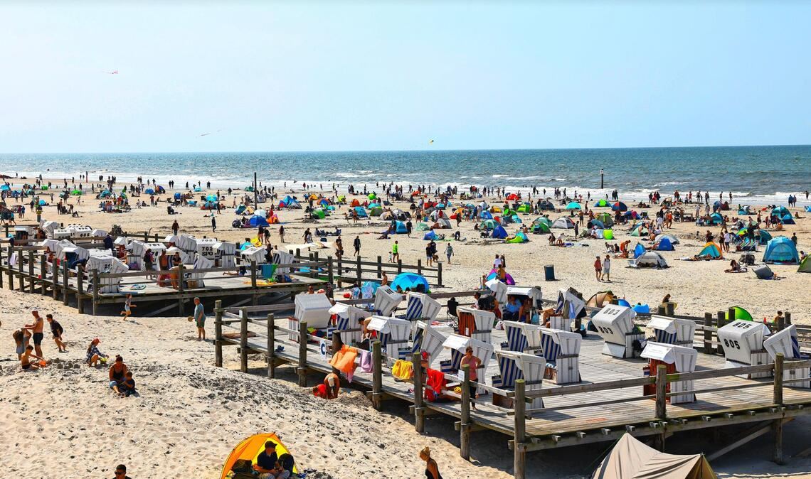 Zahlreiche Menschen sind bei strahlendem Sonnenschein am Strand von St. Peter Ording an der Nordsee unterwegs. (Archivbild)