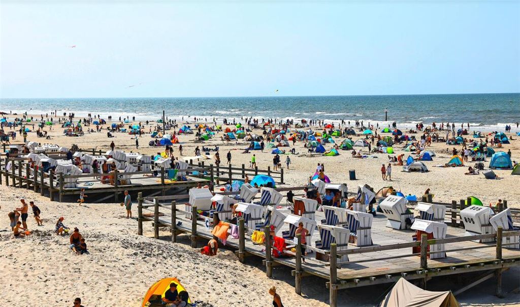 Zahlreiche Menschen sind bei strahlendem Sonnenschein am Strand von St. Peter Ording an der Nordsee unterwegs. (Archivbild)