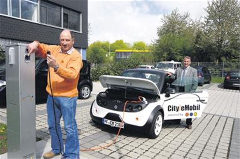 Zum Elektro-Fahrzeug gleich die passende Tankstelle installiert: an der Steckdose Elektro-Abteilungsleiter Uwe Pfisterer, am Fahrzeug Prokurist Matthias Bosch. 
Foto: Kollros 