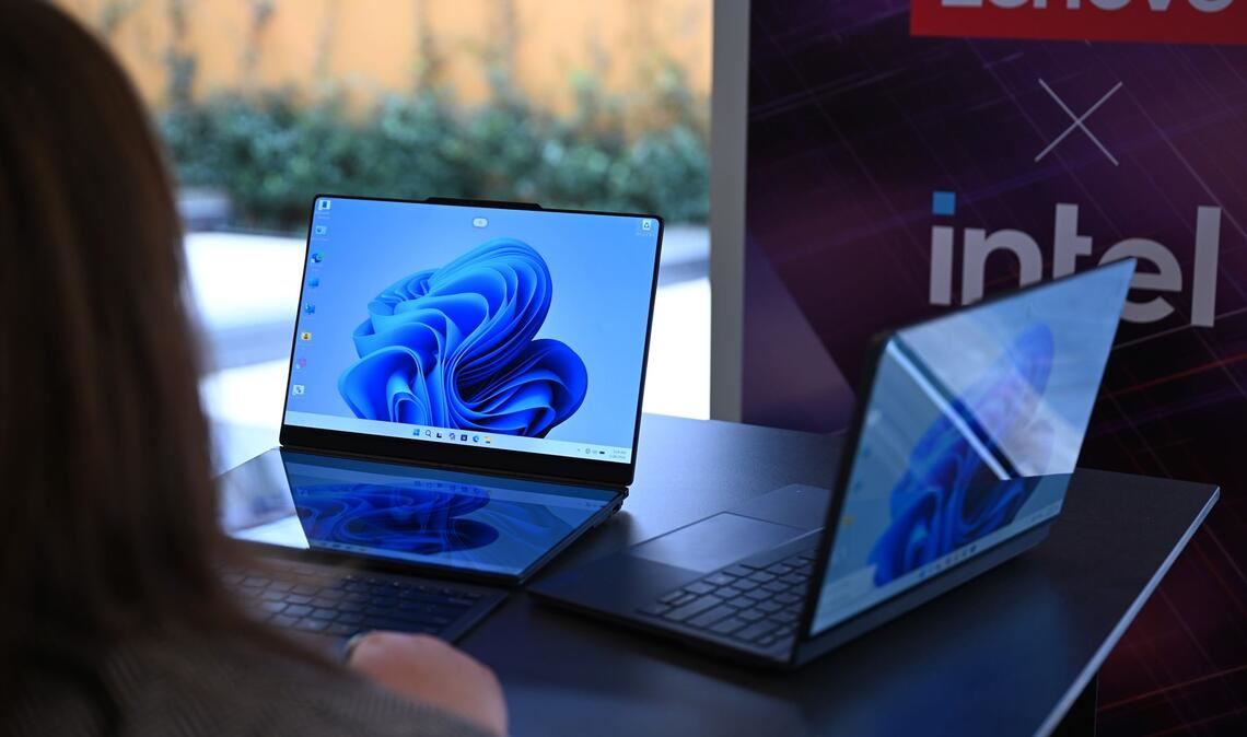 Zwei Lenovo-Laptops, die jeweils zwei Bildschirme haben: Rechts ist der zweite Bildschirm auf der Rückseite des ersten Bildschirms und links sind die beiden Bildschirme nebeneinander montiert - einer liegt vor der Tastatur und dahinter steht der zweite Bildschirm.