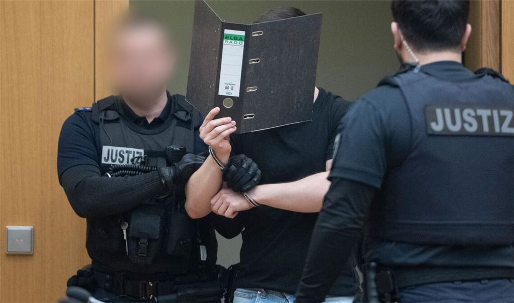 Zwei der Männer verdeckten beim Betreten des Gerichtssaals ihr Gesicht.