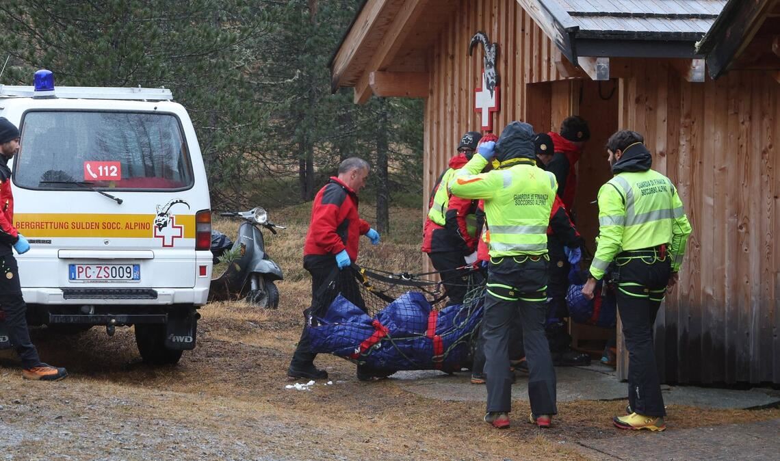Zwei der Todesopfer werden zu einer Hütte getragen.