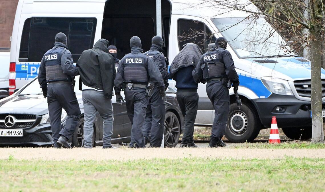 Zwei mutmaßliche Hamas-Mitglieder werden von Polizisten bei einem Hubschrauberlandeplatz von einem Hubschrauber zu einem Auto geführt. (Archivbild)